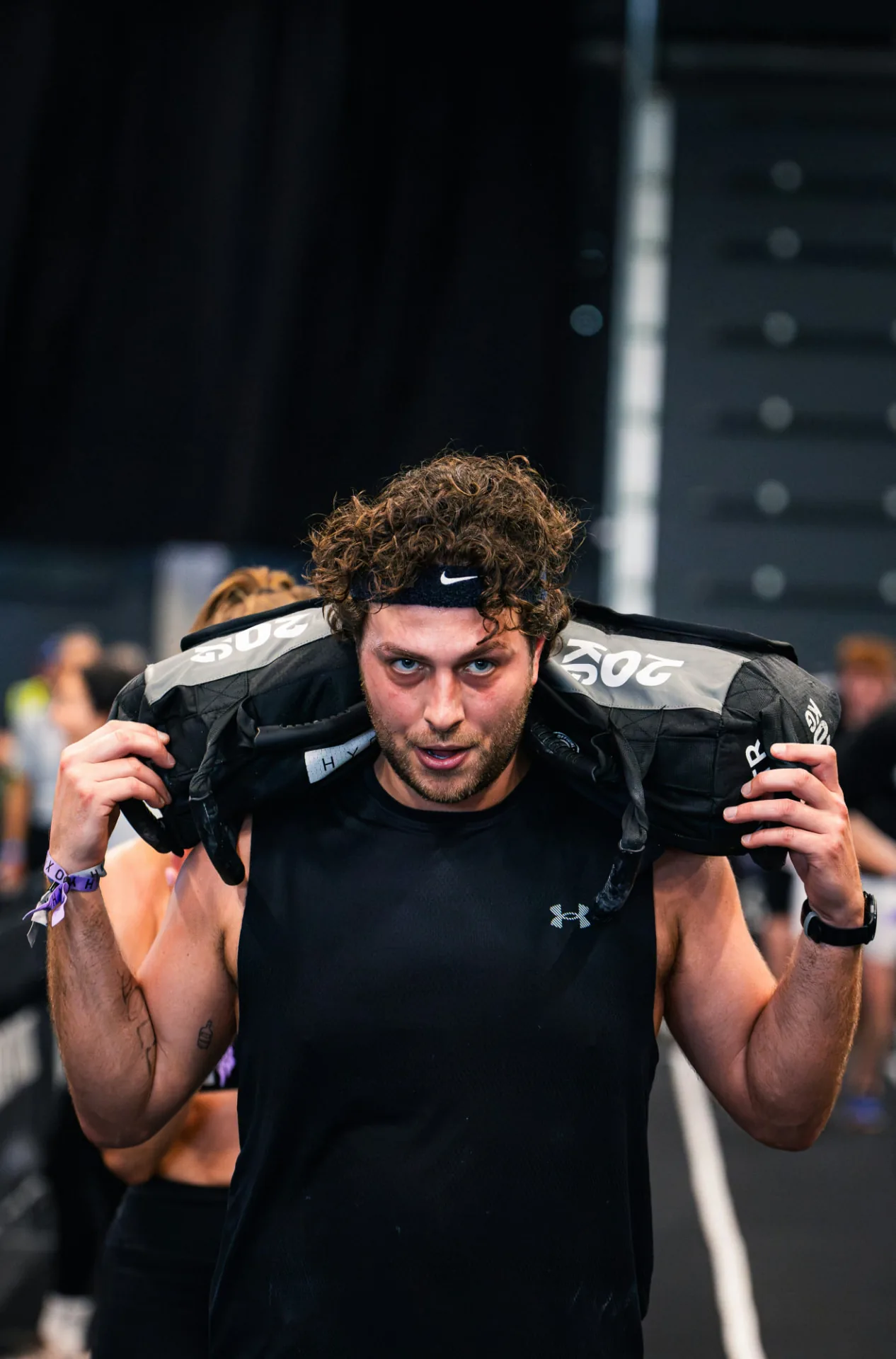 Atleta con sandbag sulle spalle in gara HYROX